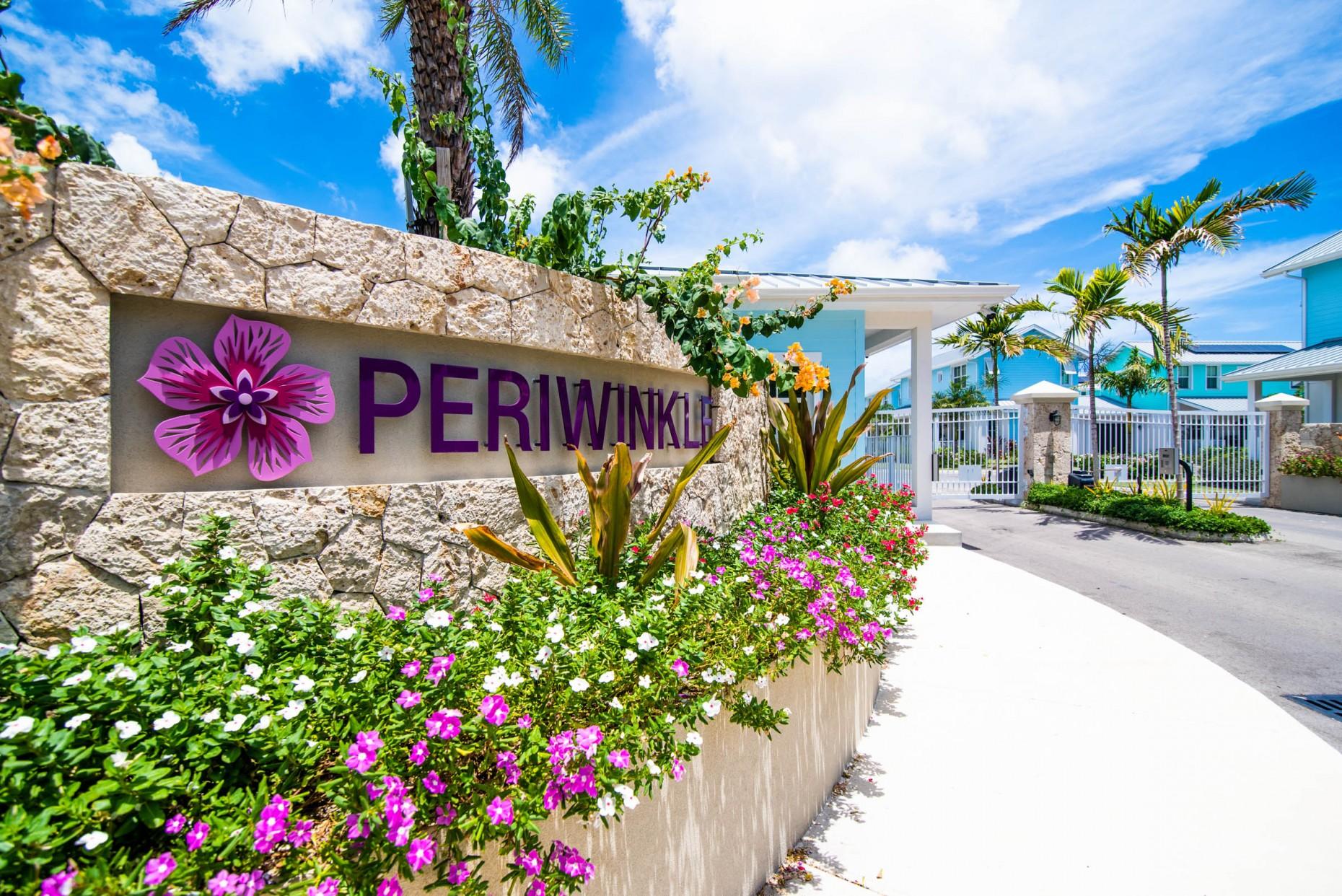 Periwinkle entrance signage at Grand Harbour, Grand Cayman, framed by tropical landscaping.